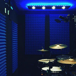 the interior of a WhisperRoom drum room with blue studio foam on the wall and a full drum kit