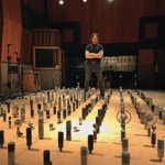 Alex Oana standing next to hundreds of microphones inside of a room
