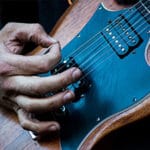 close up a man playing a Gibson SG