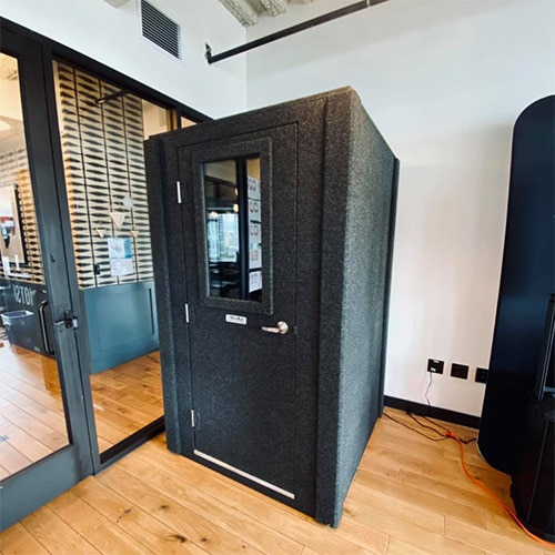 A WhisperRoom office phone booth inside of an open floor office. 
