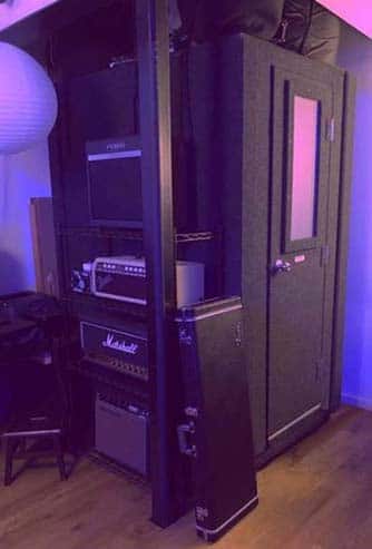 A 4' x 4' WhisperRoom vocal booth cornered in a room with guitar amps