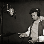 Young man wearing headphones prepares to record vocals into a condenser microphone
