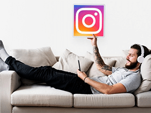 Man listening to music on the couch while holding the Instagram logo