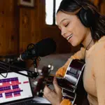 A woman recording acoustic guitar in her home studio