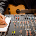 A musician writing a song at the mixing board in a recording studio
