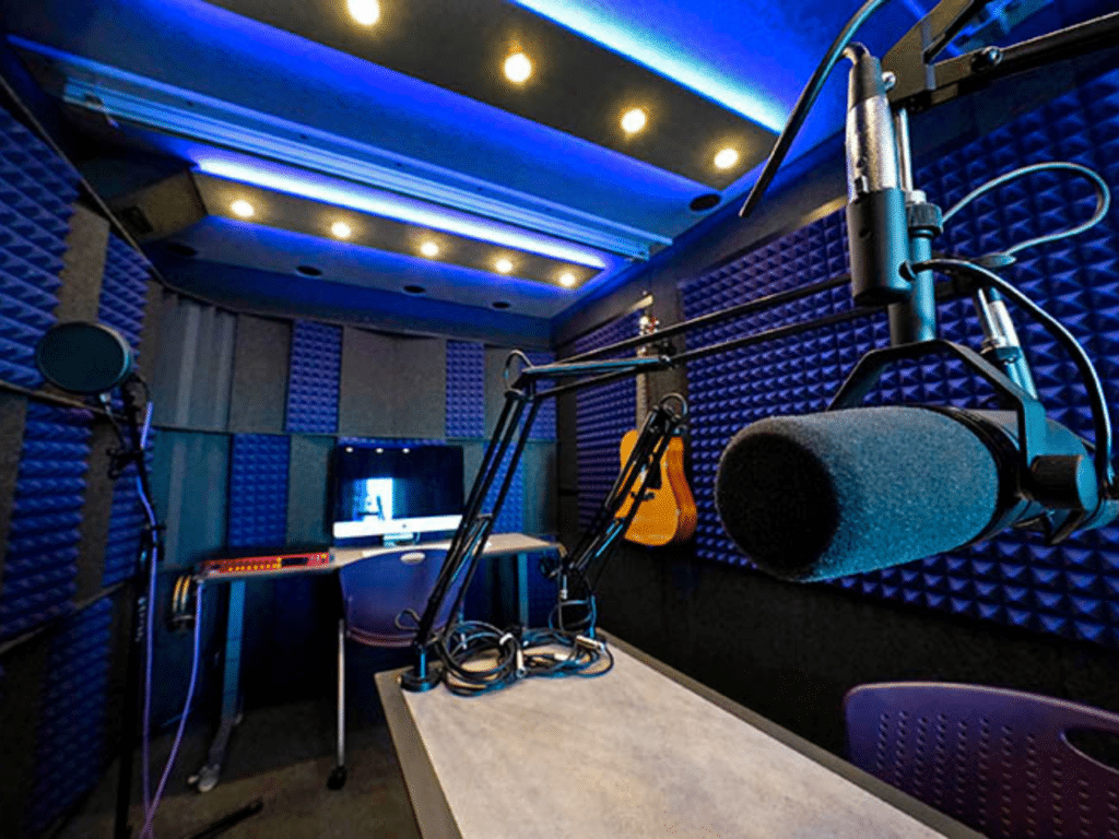 A microphone, a computer, recording gear, and a guitar inside of grand canyon university's whisperroom