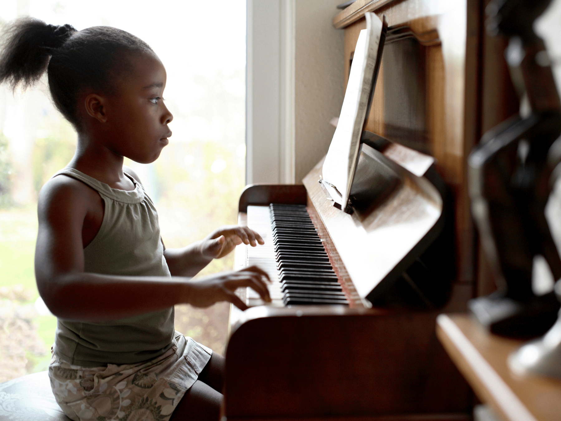 A young girl practicing piano at home