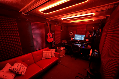 The interior or Cardinal Studios' WhisperRoom MDL 96192 E is shown with red lighting and recording studio equipment.