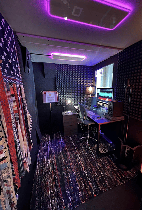 A look at the interior of a WhisperRoom  MDL 7296 S filled with a computer, a desk, and various recording gear.