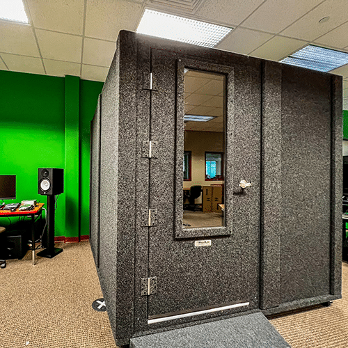 A WhisperRoom MDL 8484 S shown with a closed Wide-Access Door inside of a school's music lab.