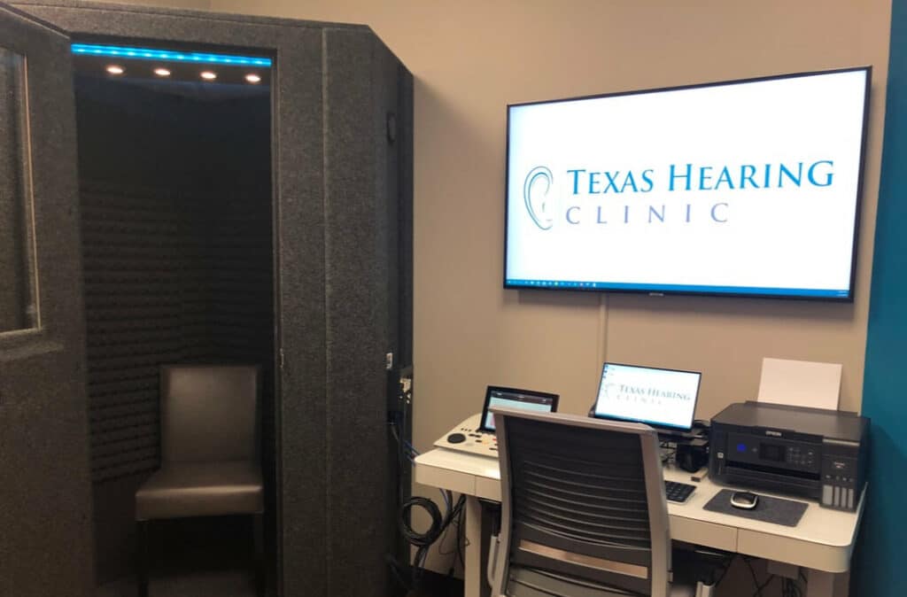 A WhisperRoom MDL 127 LP S audiology booth is shown next to testing equipment at Texas Hearing Clinic.
