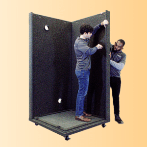 Assembly Demos: Two Men Collaboratively Assembling a WhisperRoom Soundproof Booth – One Inside Using a Screwdriver, While the Other Provides External Support.
