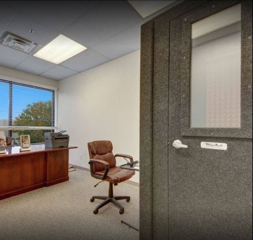 WhisperRoom Audiometric Booth in Small Audiology Office with Desk and Chair.