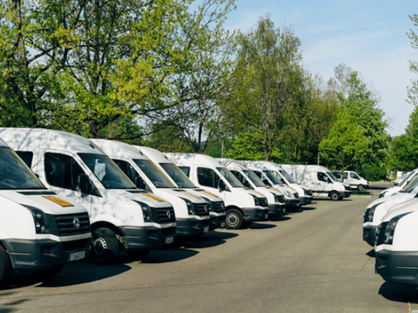 Row of white touring vans parked side by side, representing potential options for musicians or bands considering purchasing a touring vehicle.