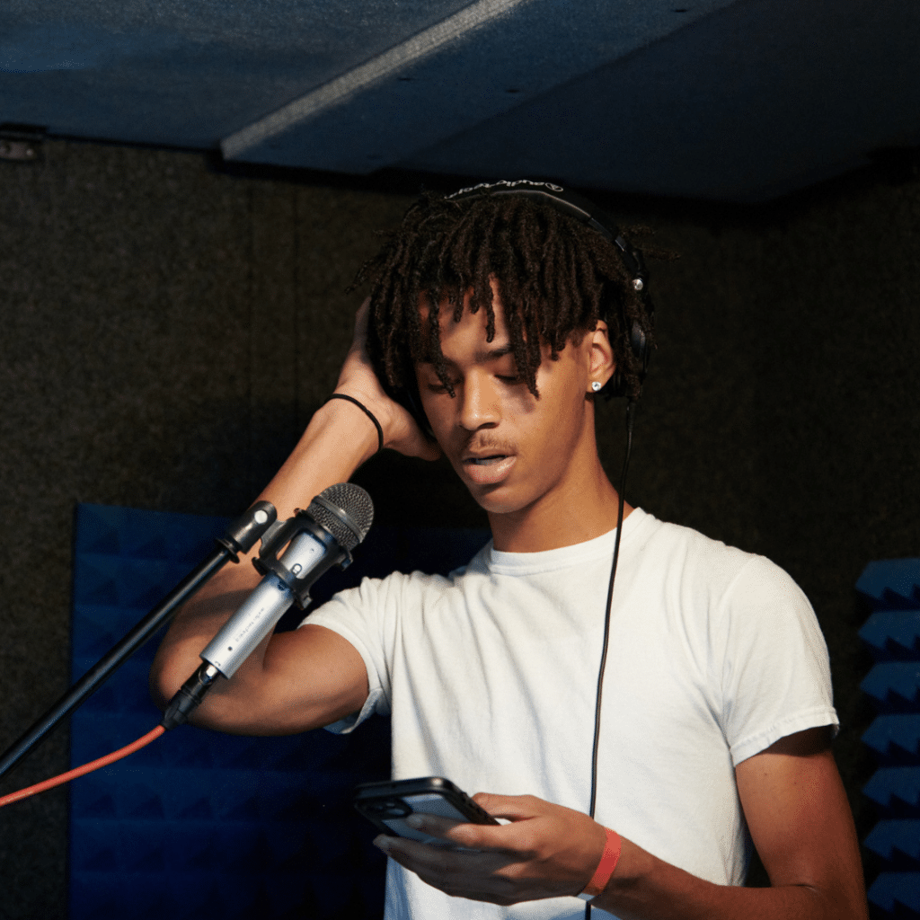 Focused young man recording clear and professional vocals for a podcast inside a WhisperRoom podcast booth, showcasing optimal sound isolation and quality.