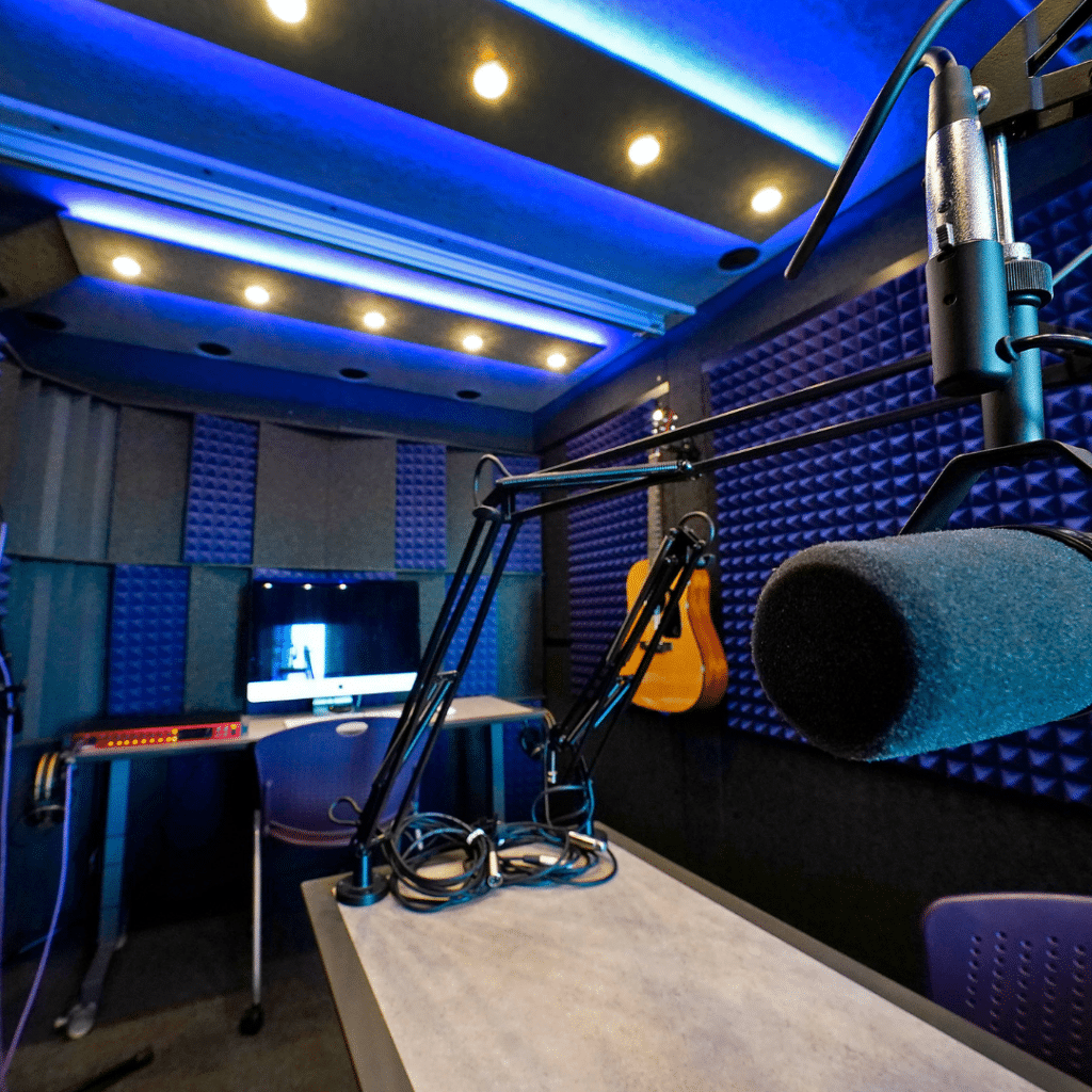 Setup for guitar recording in GCU's WhisperRoom Recording Booth, featuring a table-mounted microphone, computer, and essential recording equipment.