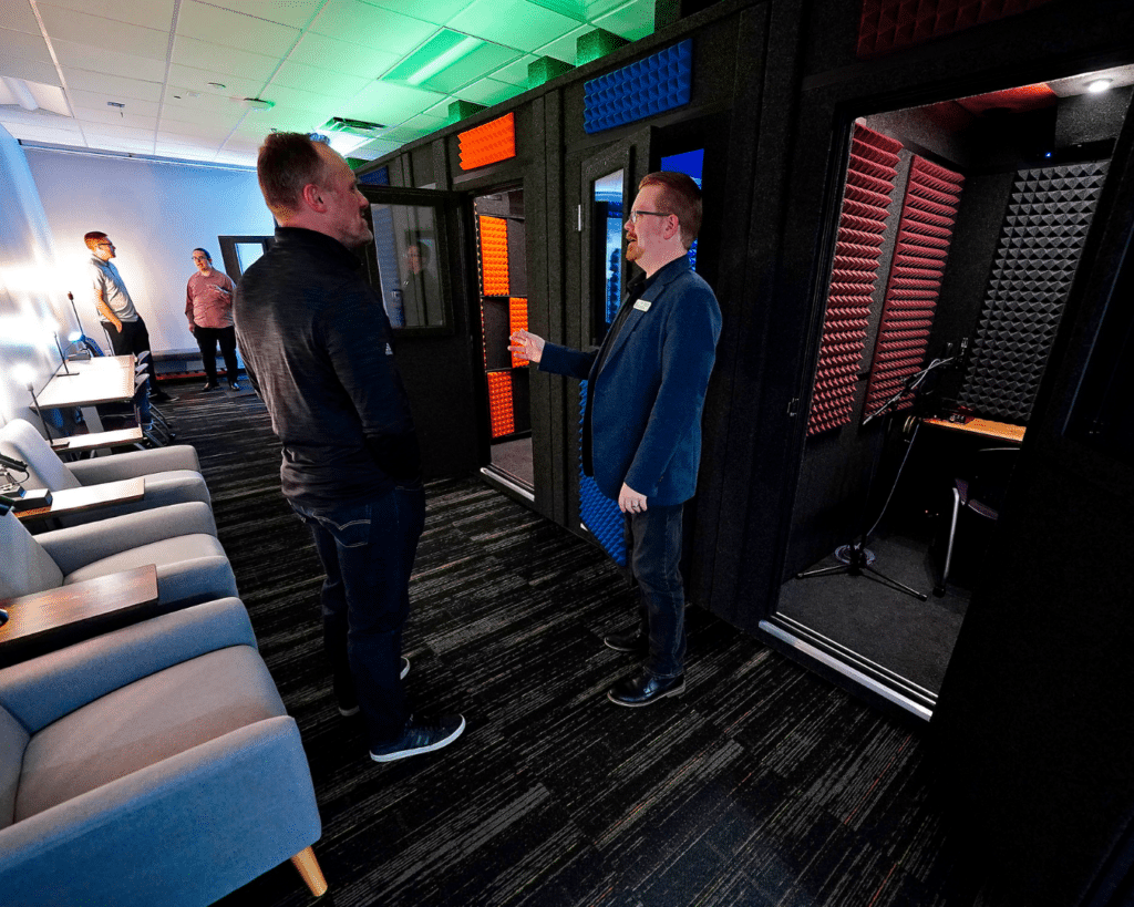 Image displaying GCU's recording lab, highlighting a room filled with WhisperRooms. Faculty members are engaged in conversation with visitors during a tour, showcasing the versatile use of WhisperRooms in the educational environment.