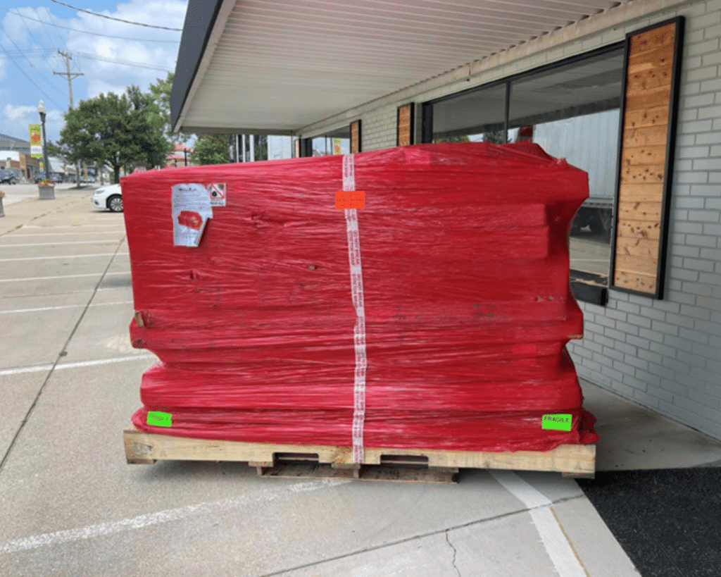 Image featuring a palletized WhisperRoom order placed next to the front of a business, awaiting further handling.