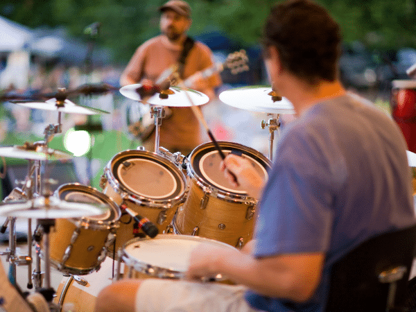 Featured image for the article "8 Ways Musicians Can Protect Their Hearing" that shows a drummer and bass player performing live without hearing protection.